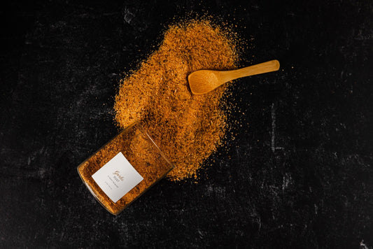 a black background with a jar of garlic dust spilled out with a wooden spoon