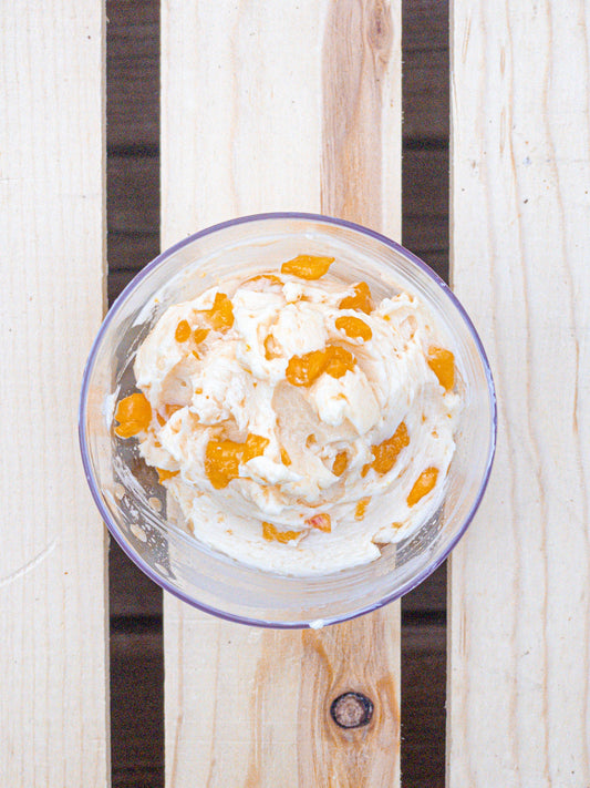 image of a compound butter with chunks of peaches sitting against a wooden slat background