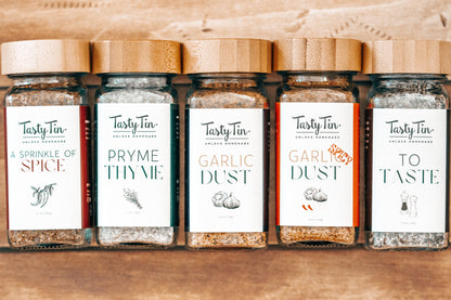 Row of Tasty Tin spice jars on a wooden surface