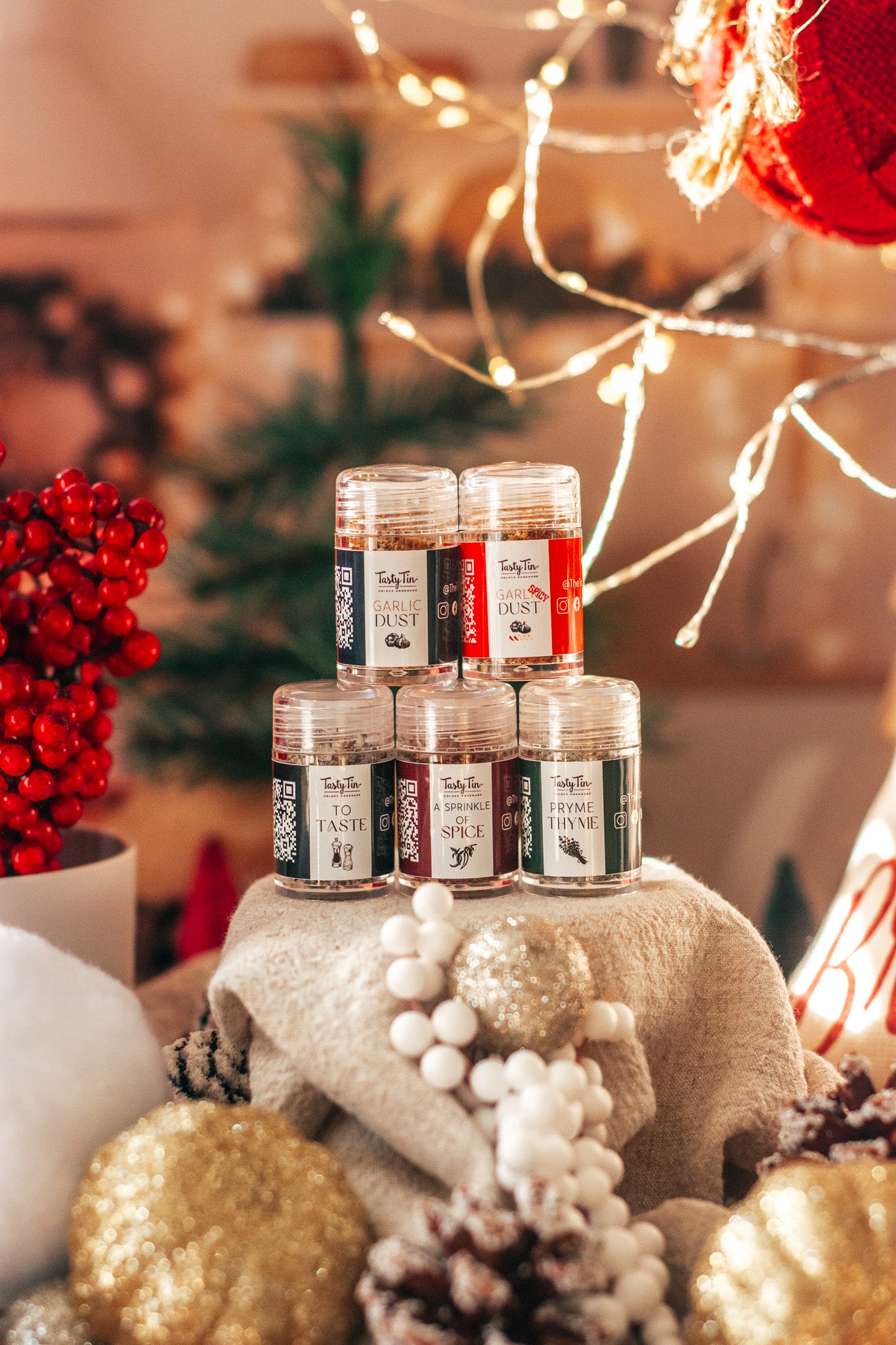 Stack of small jars with labels on a decorative stand with Christmas decorations in the background