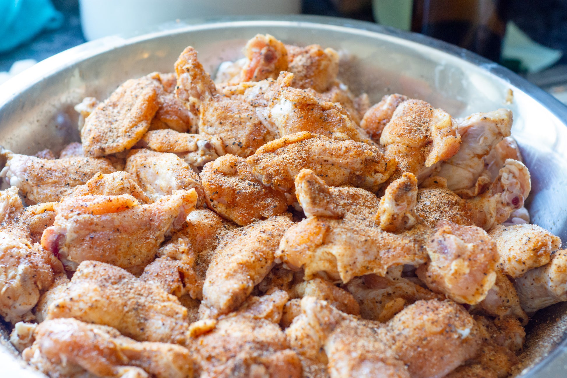 Chicken wings seasoned with garlic seasoning refill pouch spices in a metal bowl ready for cooking