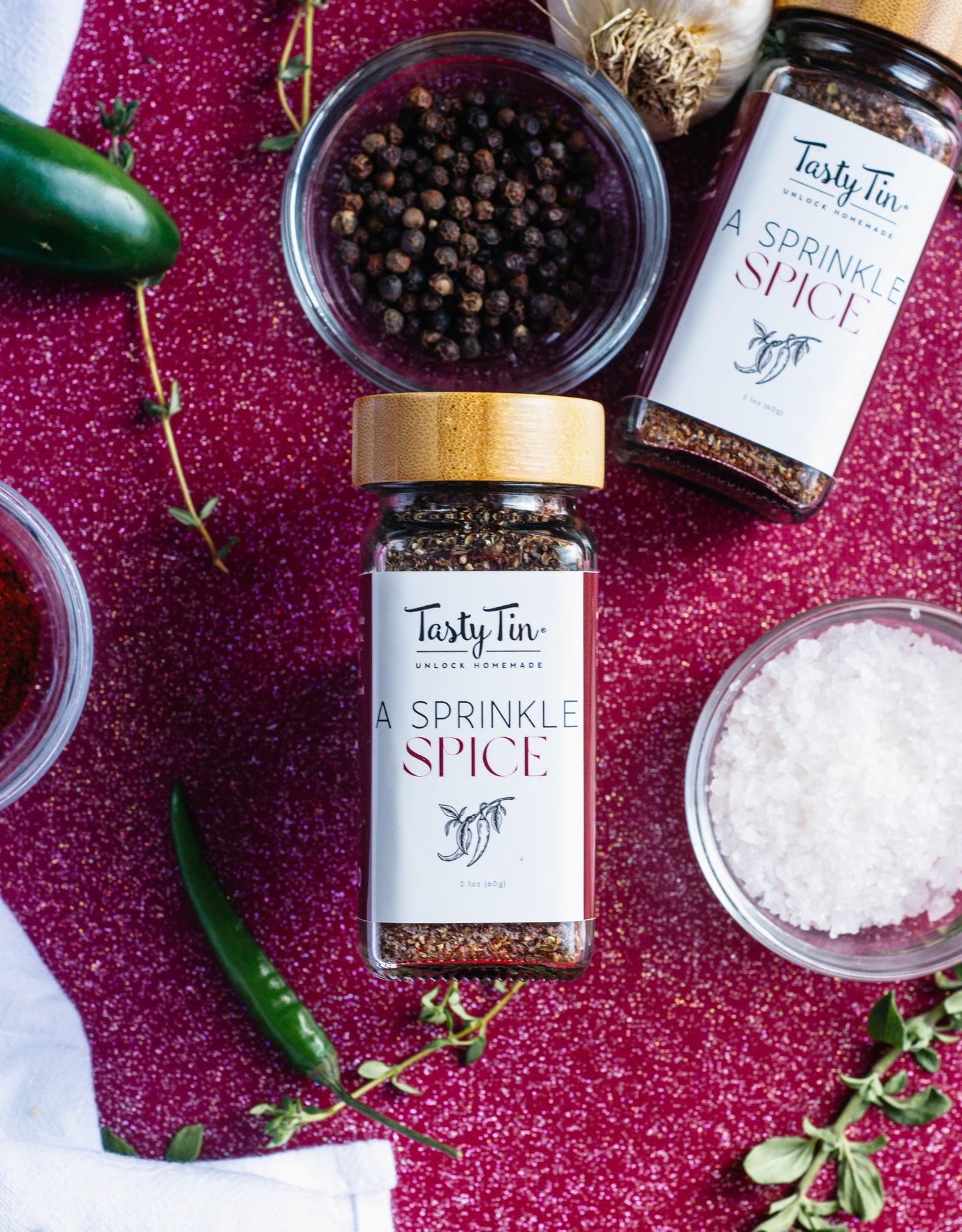 Tasty Tin gourmet spice shaker with whole peppercorns and coarse salt on red background