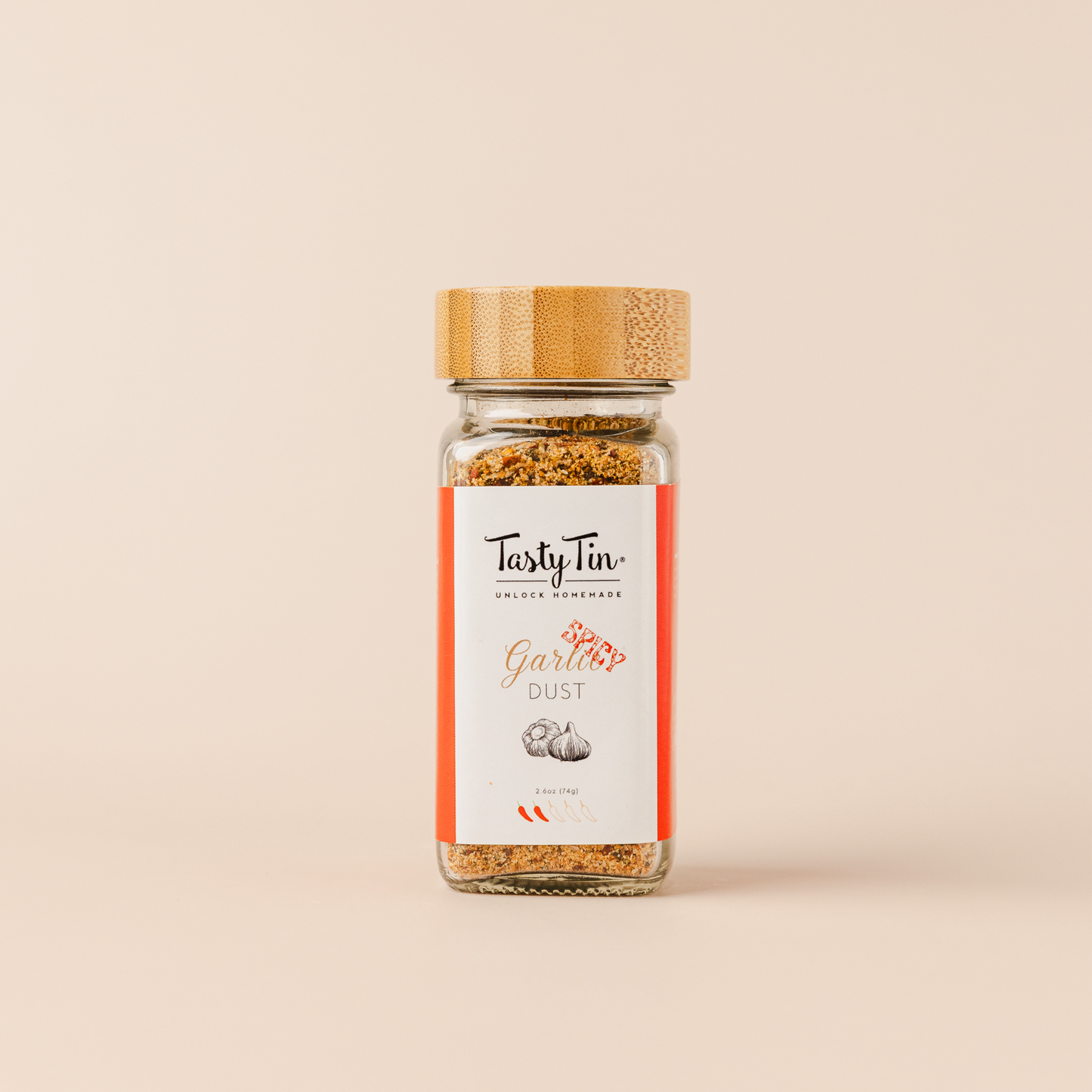 Tasty Tin spicy garlic seasoning shaker with bamboo lid and red label on beige background