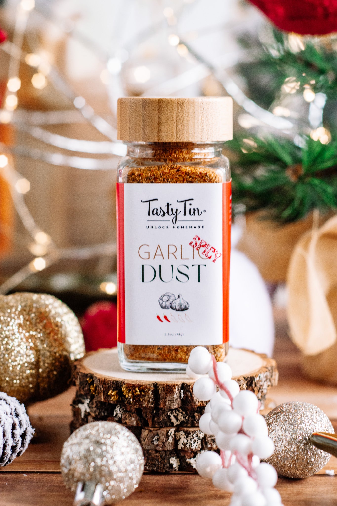 Tasty Tin spicy garlic seasoning shaker with wooden lid, placed on wooden slice with holiday decorations