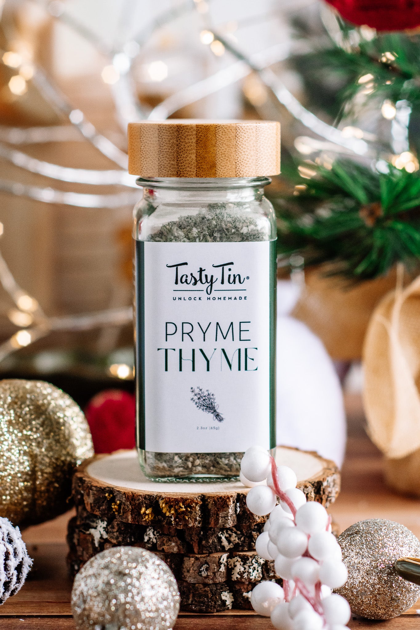 Tasty Tin thyme seasoning shaker with bamboo lid on rustic wood slice surrounded by holiday decor