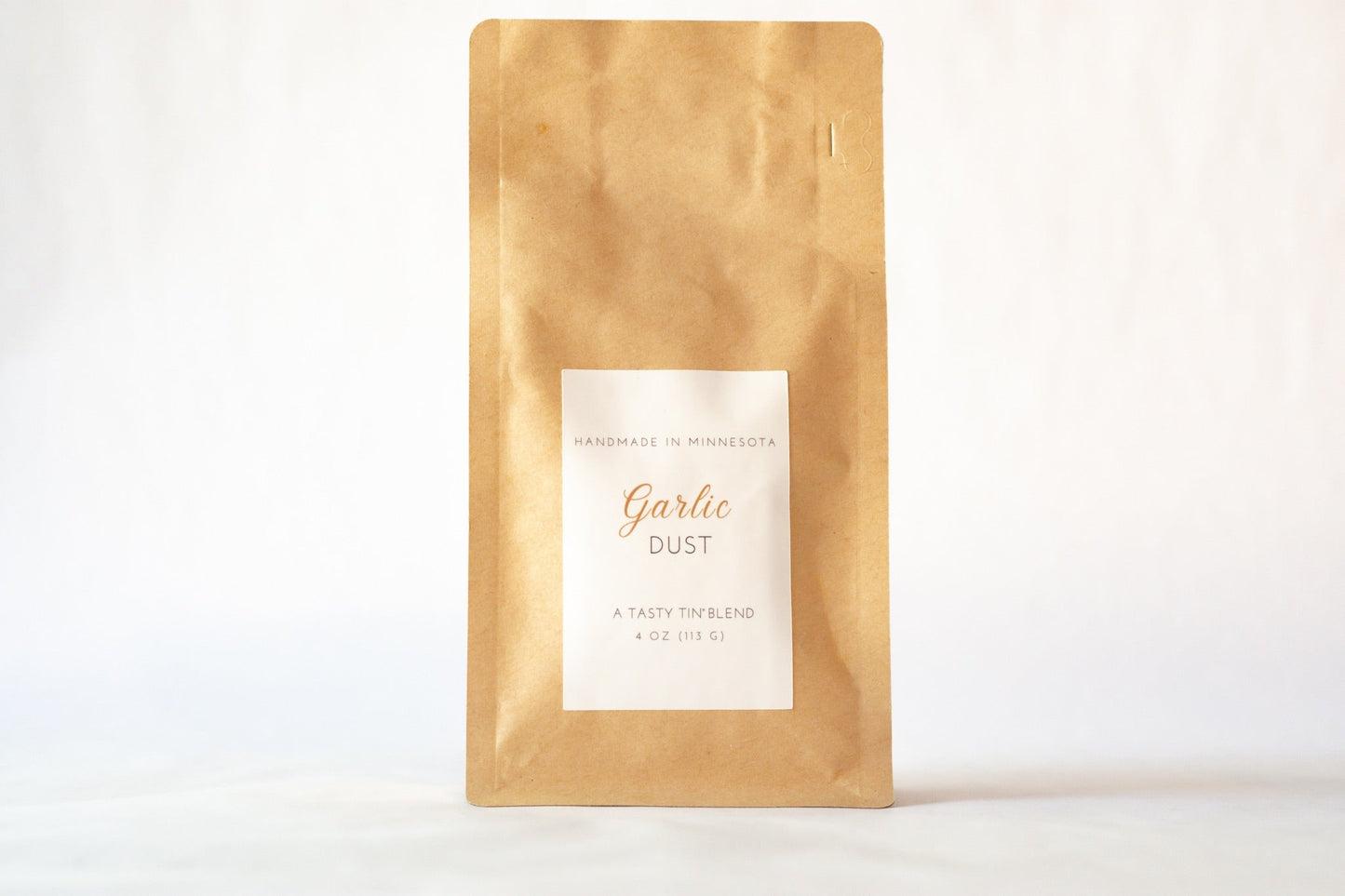 Tasty Tin garlic seasoning refill pouch in brown kraft packaging with white label on a white background